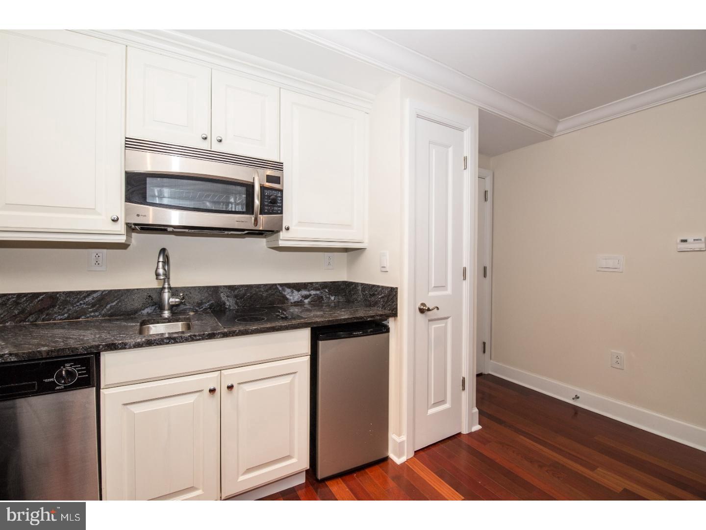 1701 Locust Street, Unit 1517 Philadelphia, PA 19103 - Photo 5 of 16 a kitchen with stainless steel appliances granite countertop a stove a microwave and a white cabinets
