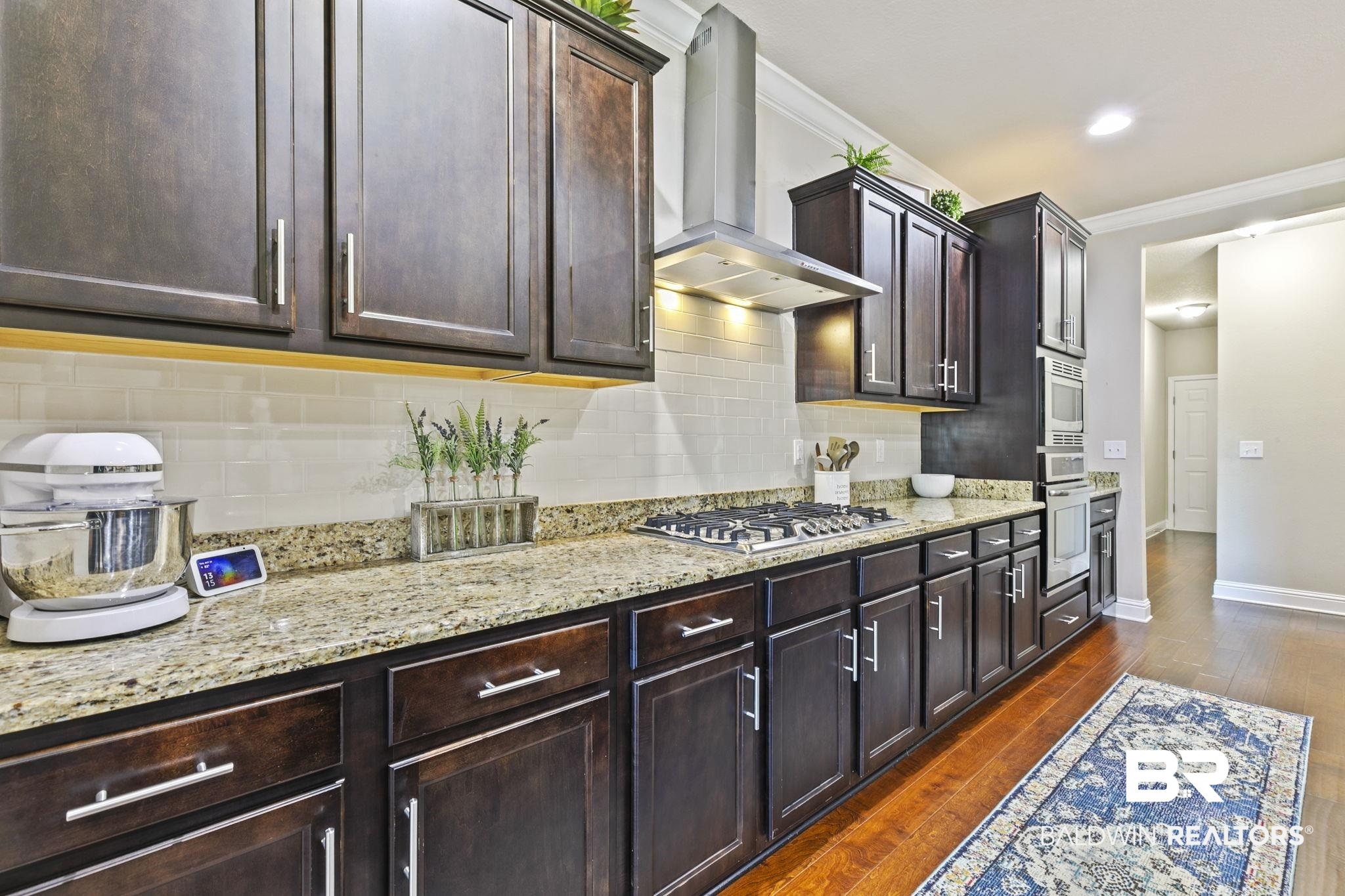 31500 Spoonbill Road Daphne, AL 36527 - Photo 20 of 85 Kitchen featuring stainless steel appliances, dark hardwood / wood-style floors, crown molding, wall chimney range hood, and decorative backsplash