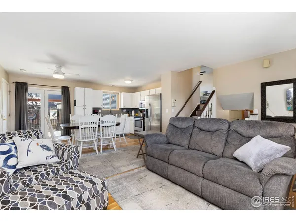 a living room with furniture kitchen view and a wooden floor