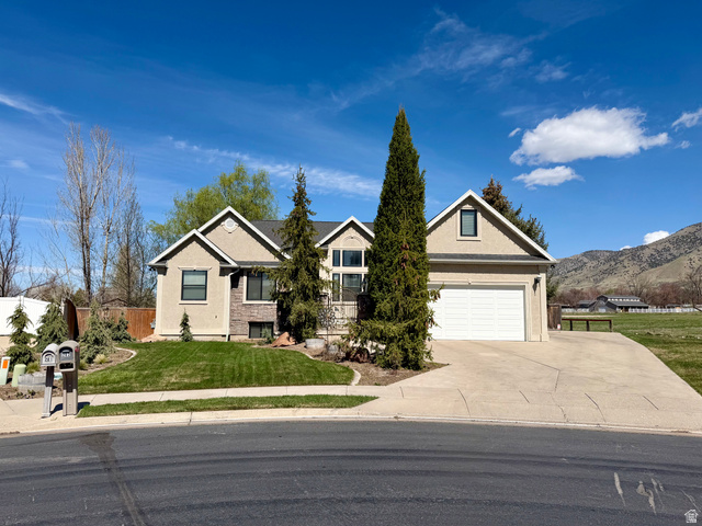 202 375 West Providence, UT 84332 - Photo 1 of 61 View of front facade with stucco siding, concrete driveway, an attached garage, and a mountain view
