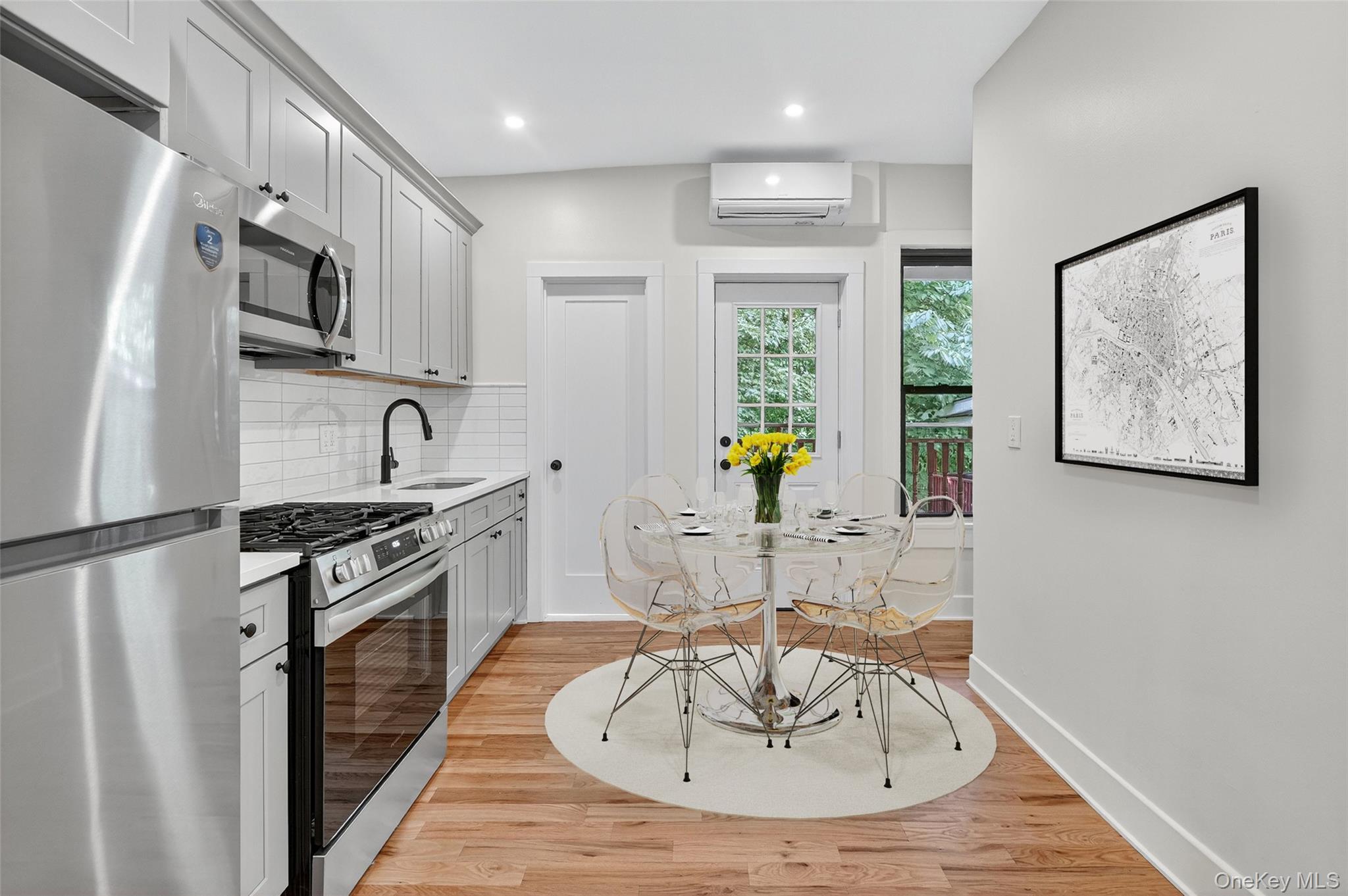 79 Main Street, Unit 2E Ossining, NY 10562 - Photo 9 of 20 a kitchen with stainless steel appliances granite countertop a sink a stove a refrigerator a microwave a dining table and chairs with wooden floor