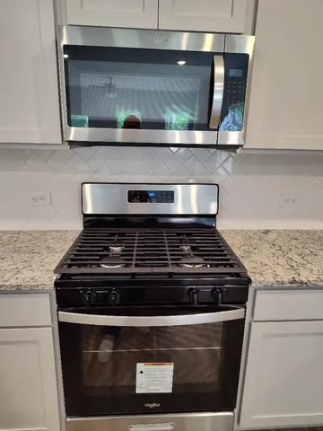a kitchen with granite countertop a sink and a stove top oven with wooden floor