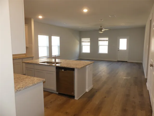 a view of a kitchen with a sink and dishwasher a refrigerator with wooden floor