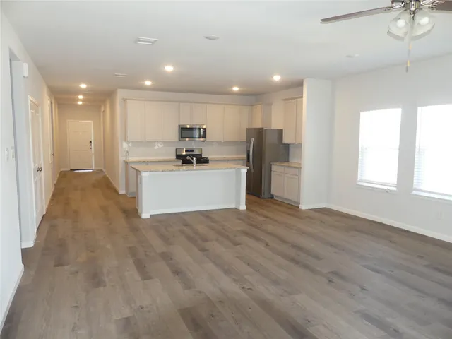 a kitchen with kitchen island granite countertop a sink a stove and refrigerator