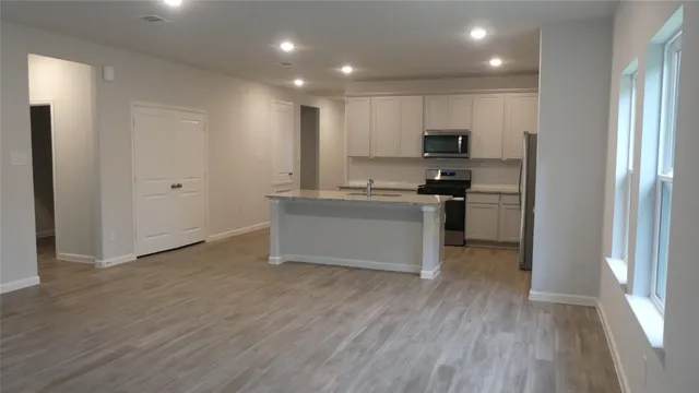 a view of an empty room with a window and wooden floor