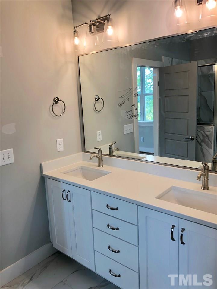 112 Roseroot Court Holly Springs, NC 27540 - Photo 7 of 30 a bathroom with a double vanity sink and a mirror