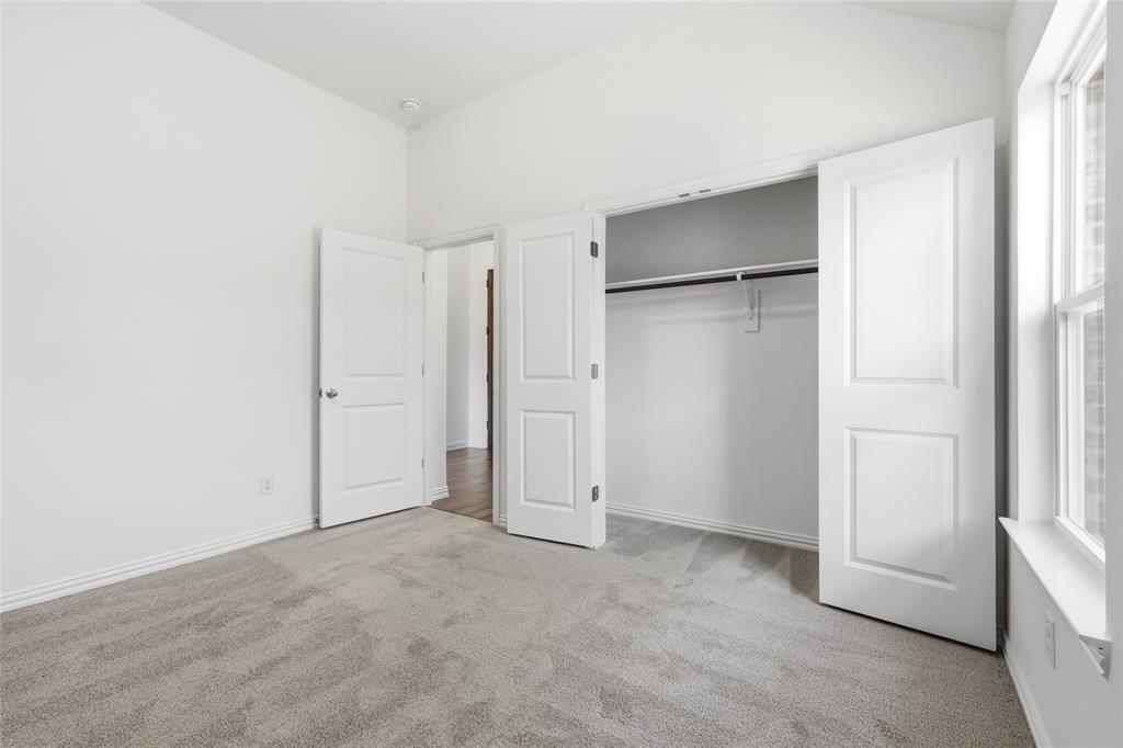 2529 Rivers W Road Anna, TX 75409 - Photo 7 of 40 Carpeted room featuring a double-door closet with shelving and hanging rod, a single window, and a vaulted ceiling