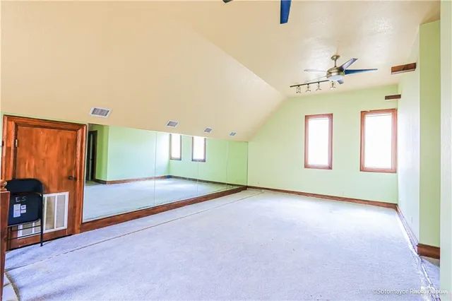 an empty room with windows and fan
