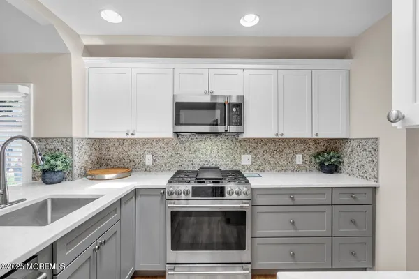 a kitchen with granite countertop white cabinets and a stove