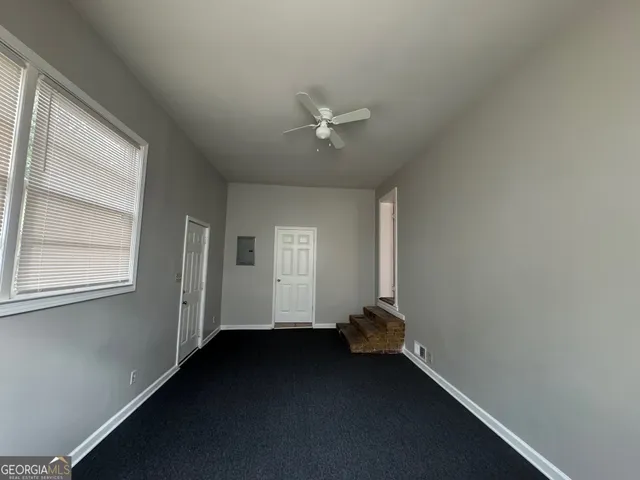 an empty room with a window and a ceiling fan