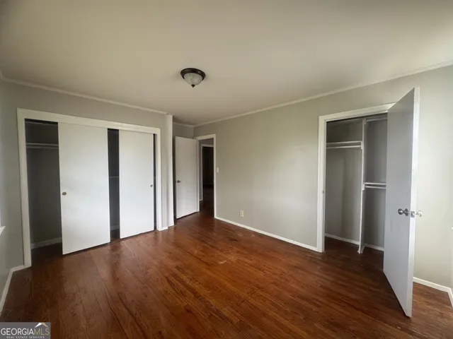 a view of an empty room with wooden floor and closet