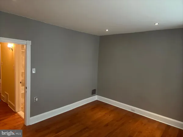 an empty room with wooden floor and entrance