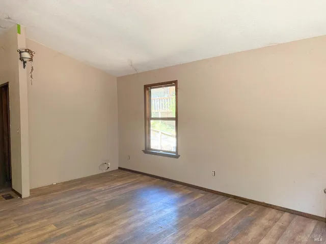 an empty room with wooden floor and window