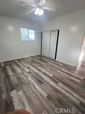 a view of an empty room with window and wooden floor