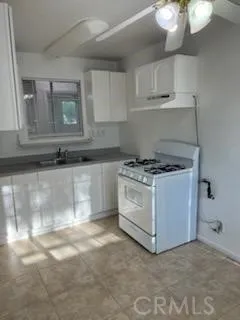 a kitchen with granite countertop a stove a sink and a white cabinets