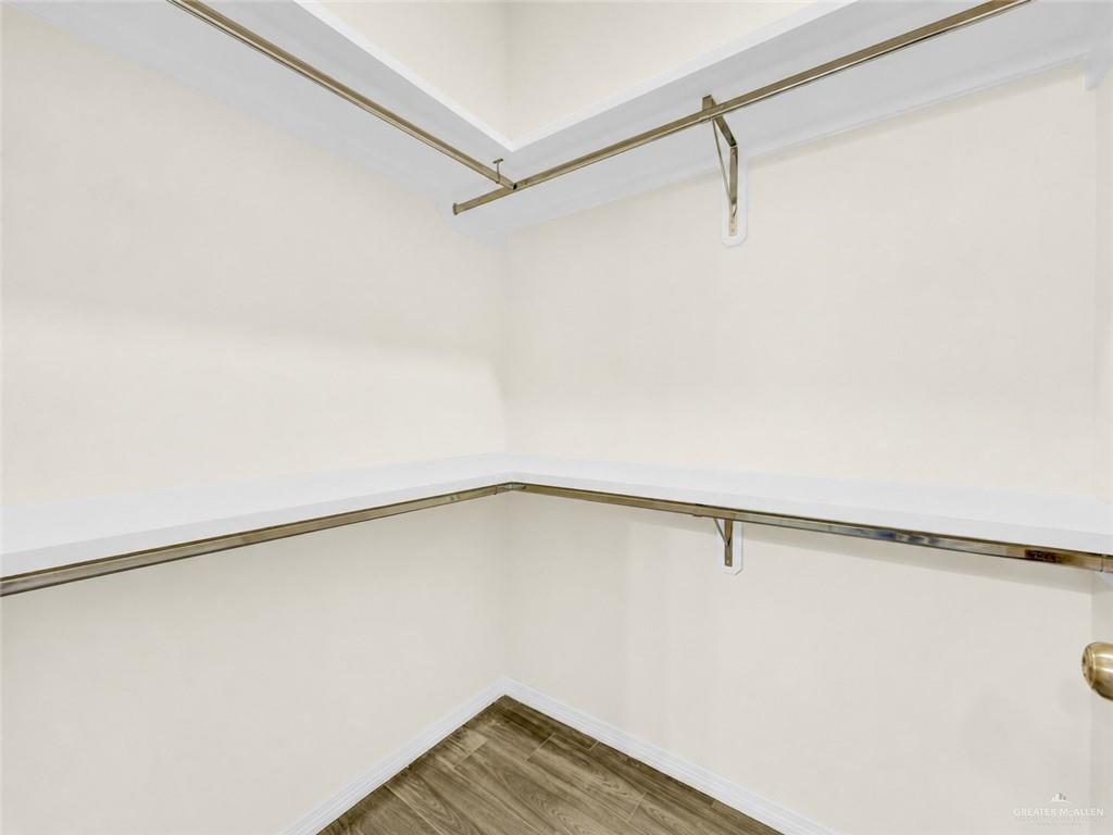 618 West 25th Street Mission, TX 78574 - Photo 7 of 8 Walk-in closet featuring white shelving, chrome hanging rods, and wood-finish flooring