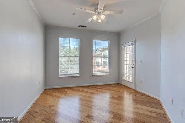 a view of empty room with wooden floor and fan