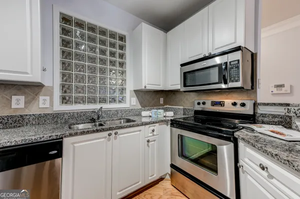 a kitchen with granite countertop a sink stove and microwave