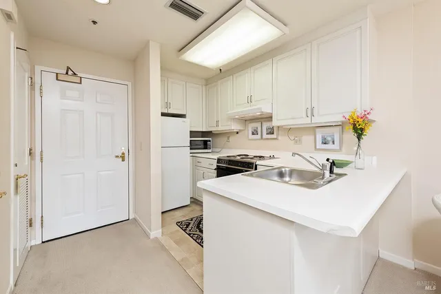 a kitchen with a sink a stove a refrigerator and white cabinets
