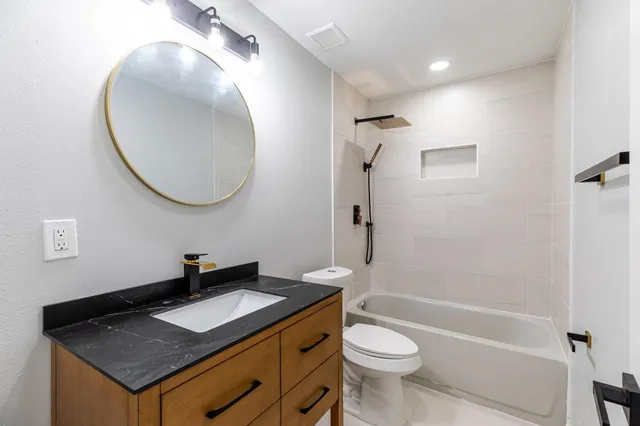 a bathroom with a granite countertop sink toilet and a mirror