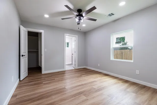an empty room with wooden floor and ceiling fan