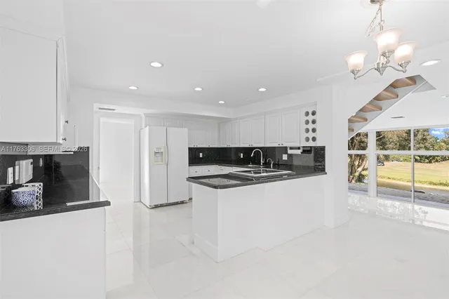 a kitchen with granite countertop white cabinets and a sink