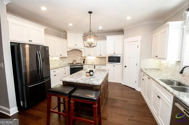 a kitchen with granite countertop a sink stove a refrigerator and white cabinets with wooden floor