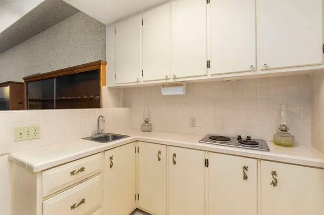 a kitchen with granite countertop white cabinets and white appliances