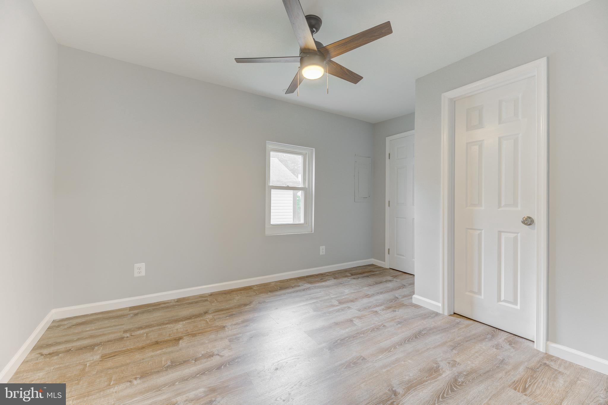 3911 3rd Street North Beach, MD 20714 - Photo 15 of 48 an empty room with wooden floor ceiling fan and windows