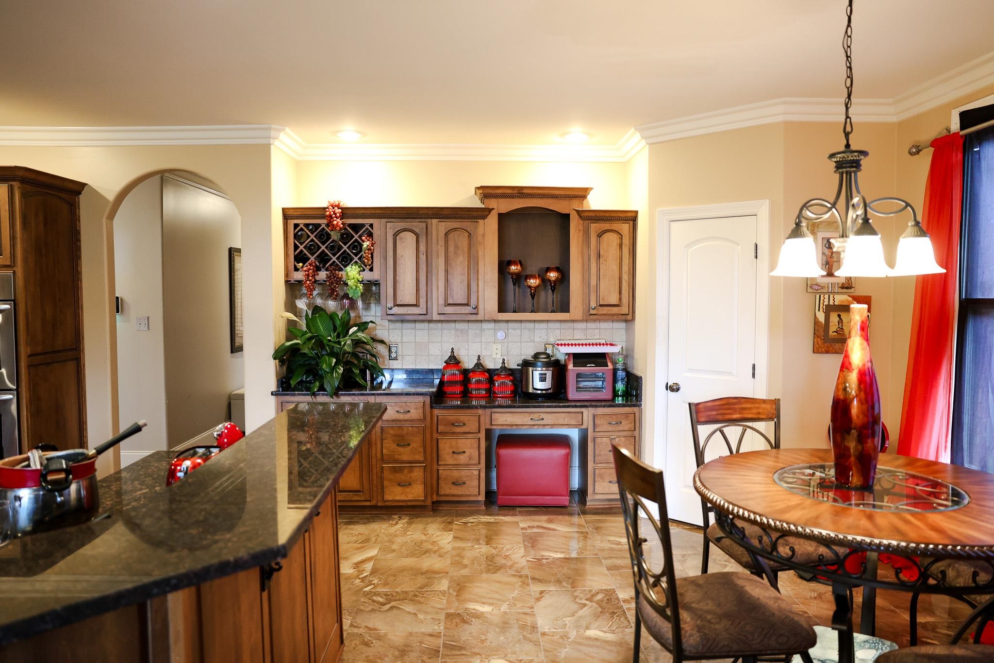 649 Ridge Springs Road Collierville, TN 38017 - Photo 16 of 35 Kitchen featuring dark stone countertops, brown cabinetry, crown molding, tasteful backsplash, and decorative light fixtures