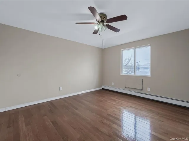 an empty room with wooden floor fan and windows