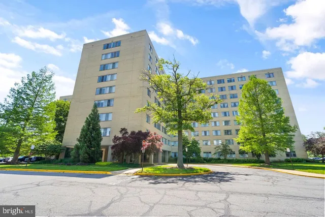 a front view of a multi story residential apartment building with yard and trees