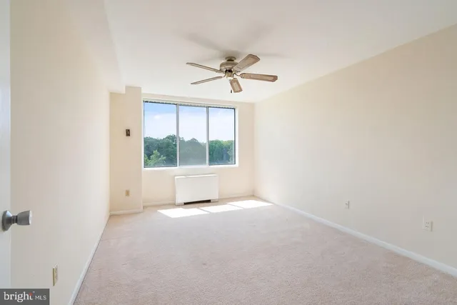 an empty room with a window and a ceiling fan