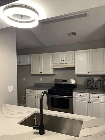 a kitchen with granite countertop a stove and white cabinets
