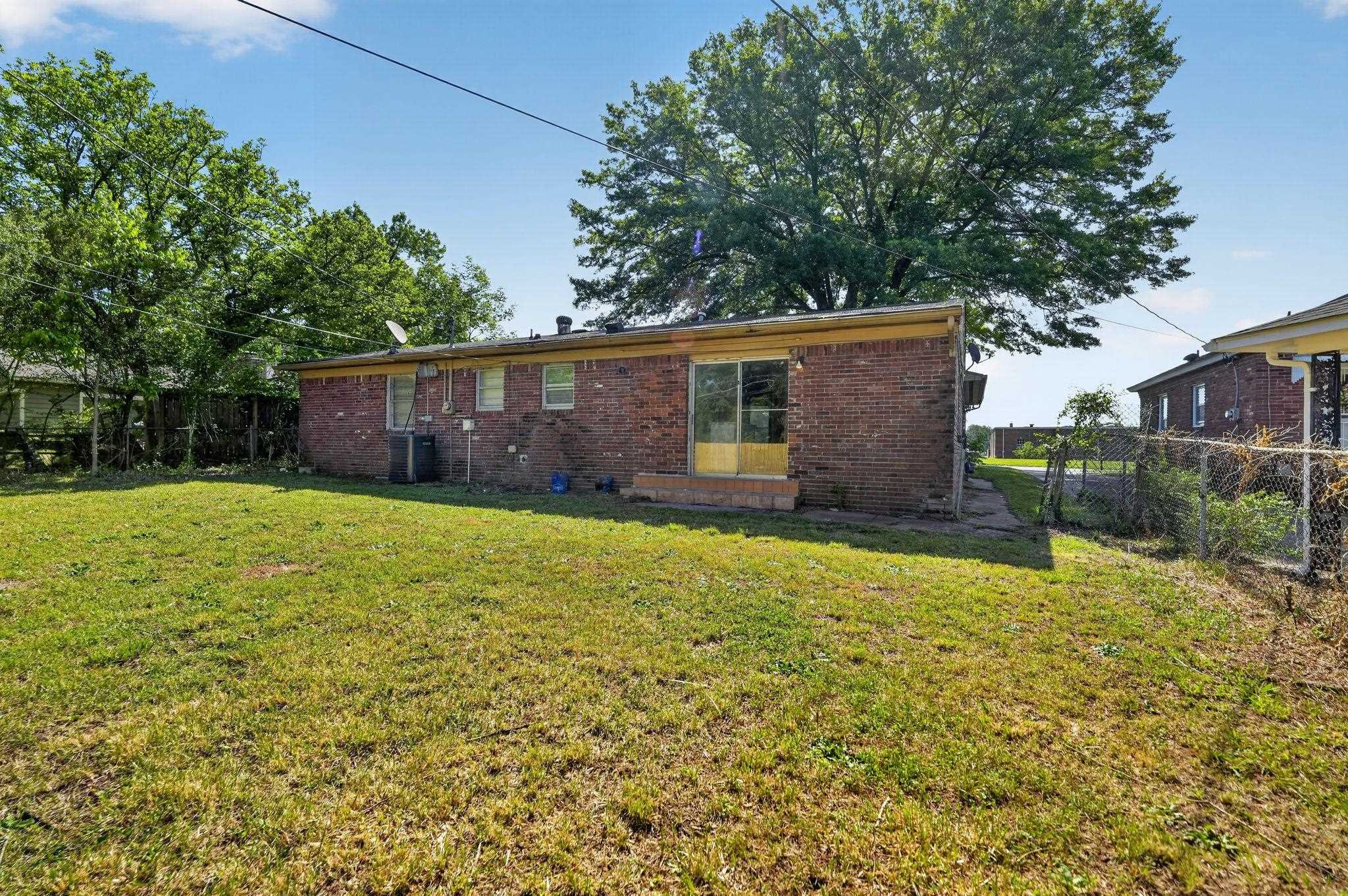 3445 Powers Road Memphis, TN 38128 - Photo 8 of 35 Expansive green lawn with mature trees and a chain-link fence