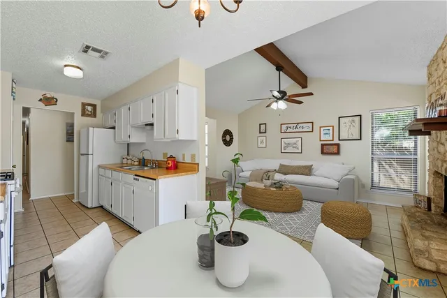 a kitchen with stainless steel appliances kitchen island granite countertop a refrigerator a sink dishwasher a dining table and chairs with wooden floor