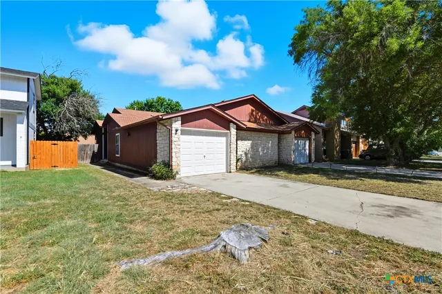 a front view of a house with a garden and trees