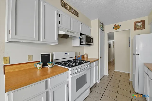 a kitchen with stainless steel appliances a sink dishwasher a refrigerator a stove and white cabinets with wooden floor