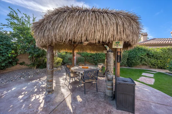 a view of a patio with table and chairs under an umbrella with a small yard