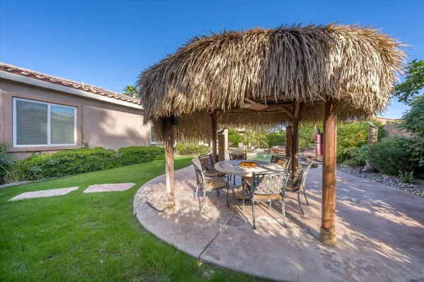 a view of a patio with table and chairs under an umbrella next to a yard
