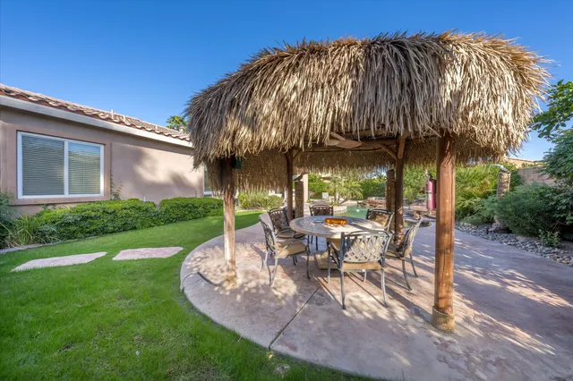 a view of a patio with table and chairs under an umbrella next to a yard