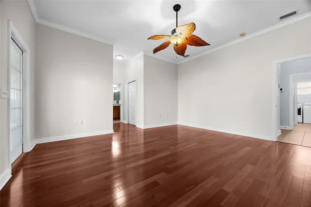 a view of an empty room with wooden floor ceiling fan
