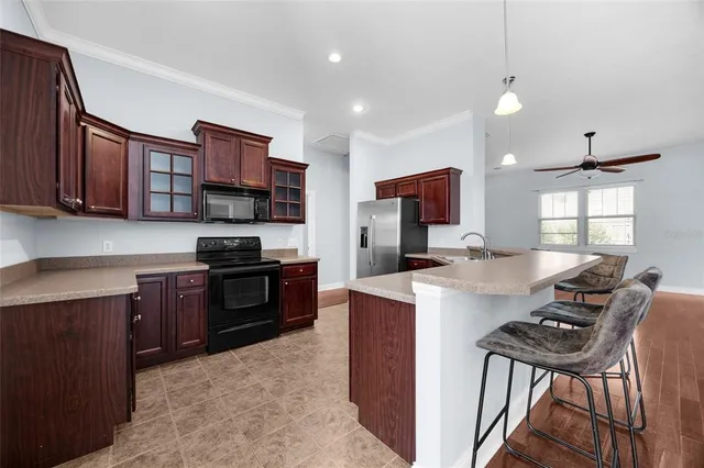 a kitchen with a stove a sink a kitchen island with chairs and wooden cabinets