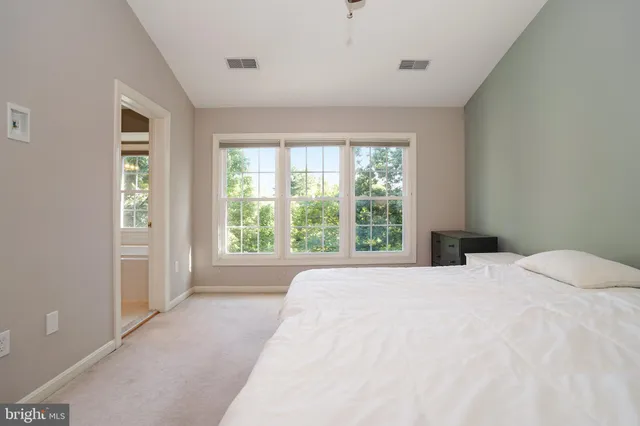 a large white bed in a room next to a window