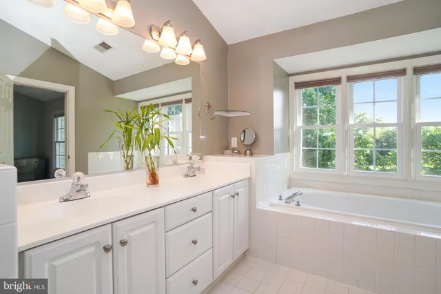 a bathroom with a double vanity sink bathtub and next to a window
