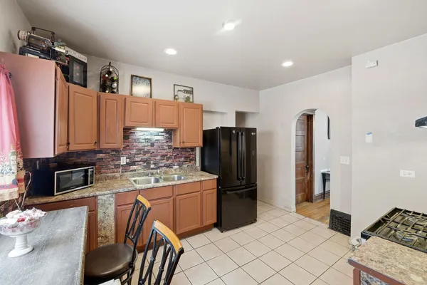 a kitchen with stainless steel appliances kitchen island granite countertop a refrigerator and a stove top oven