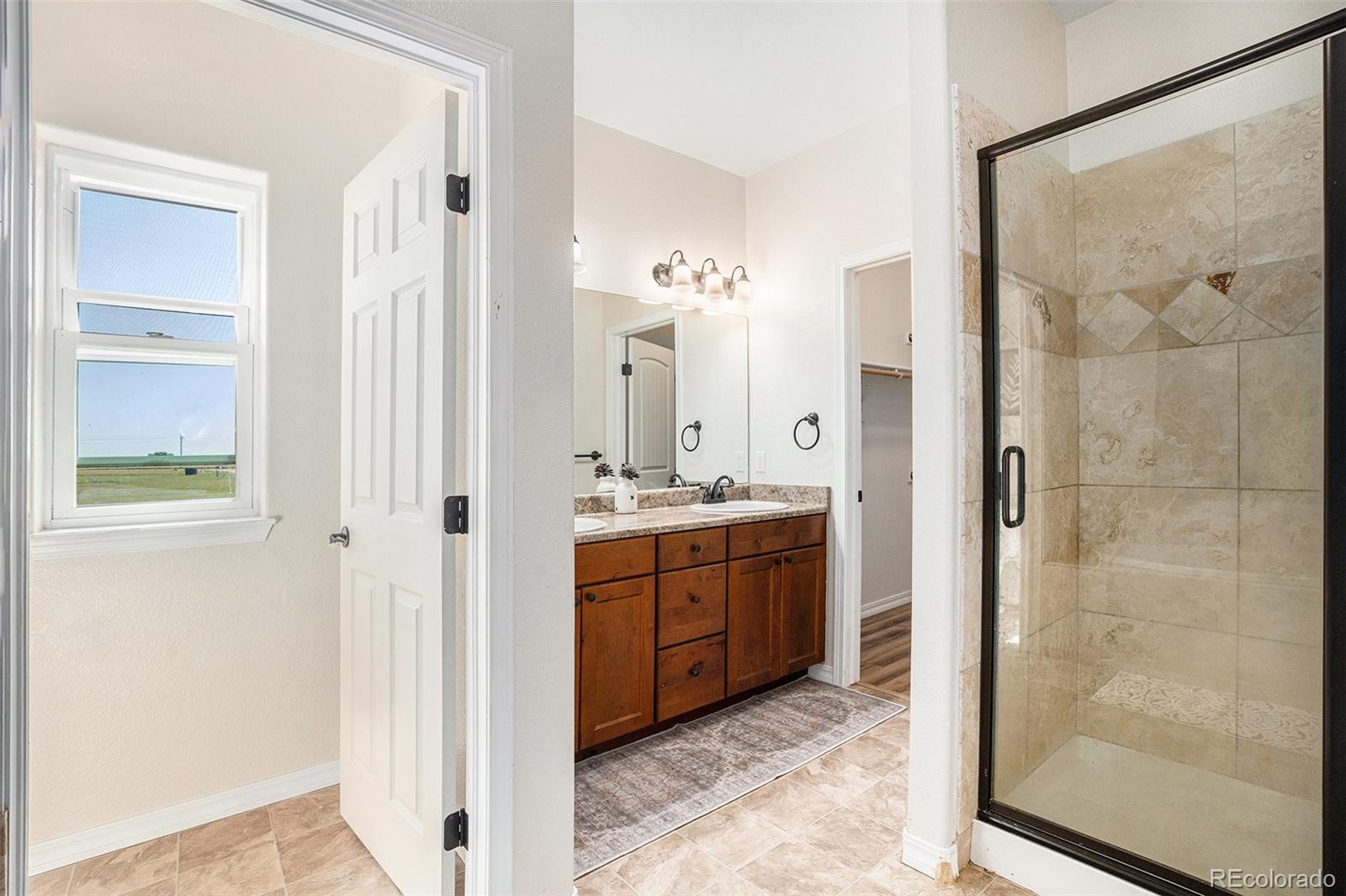 16690 Rabbit Track Trail Colorado Springs, CO 80930 - Photo 12 of 25 a bathroom with a granite countertop sink a mirror and a shower