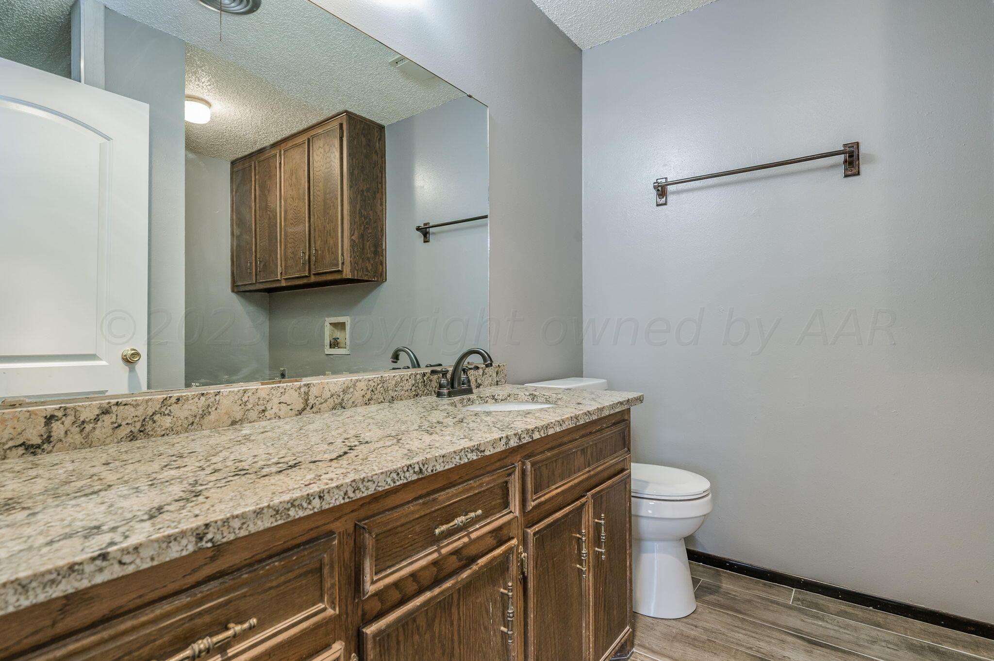 1909 Howard Drive Amarillo, TX 79106 - Photo 11 of 19 a bathroom with a granite countertop sink a toilet and mirror