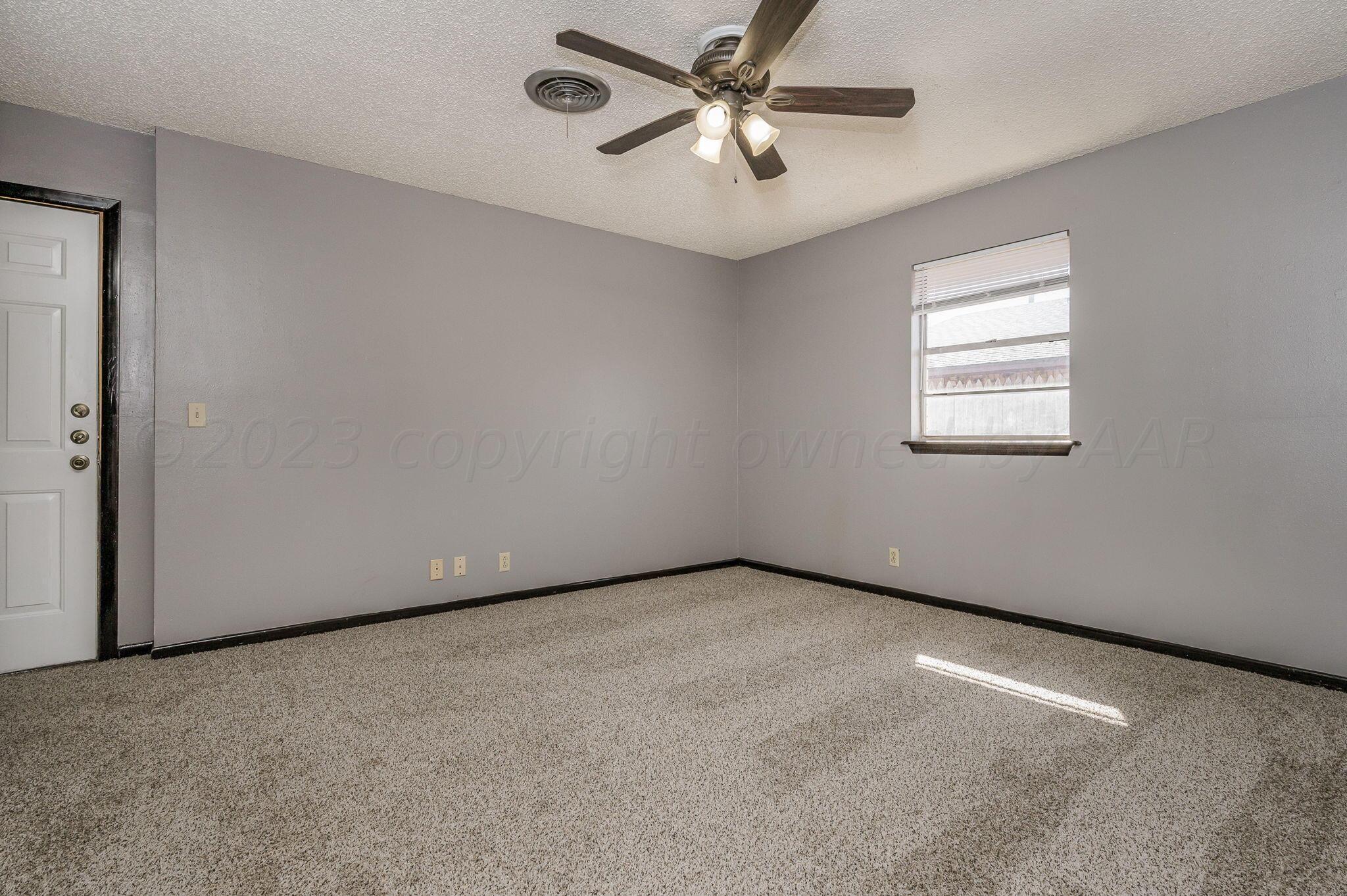1909 Howard Drive Amarillo, TX 79106 - Photo 9 of 19 an empty room with a chandelier fan and windows