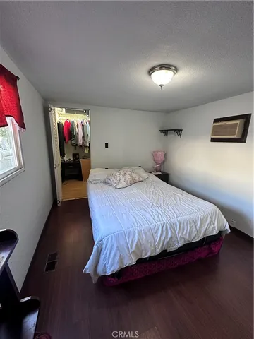 a bedroom with a bed mirror and wooden floor